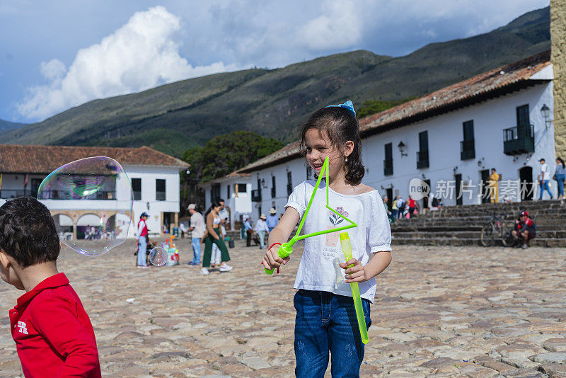 拉丁裔兄弟们正在博雅卡(Boyaca)旅行，更确切地说，是在莱瓦别墅(Villa de Leyva)的历史广场上玩大泡泡。